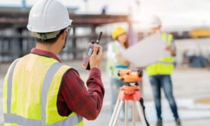 Land surveyor on a commercial property site conducting an ALTA survey with team reviewing plans in Georgia