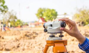 Land surveyor adjusting a level instrument during a topographic survey at a construction site in Georgia.
