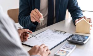 Real estate closing with contract, keys, and documents showing how a flood elevation certificate helps prevent NFIP delay issues