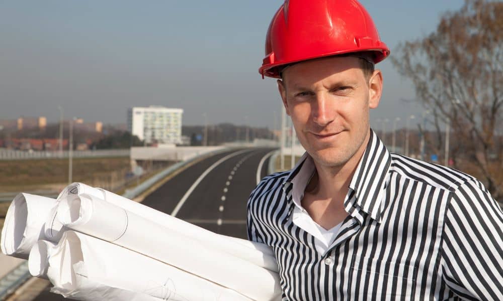 Transportation engineer reviewing highway construction plans on site
