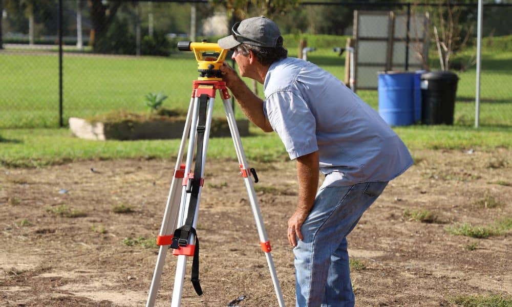 Surveyor measuring a residential property while homeowners look for a property surveyor near me to check boundaries and land conditions