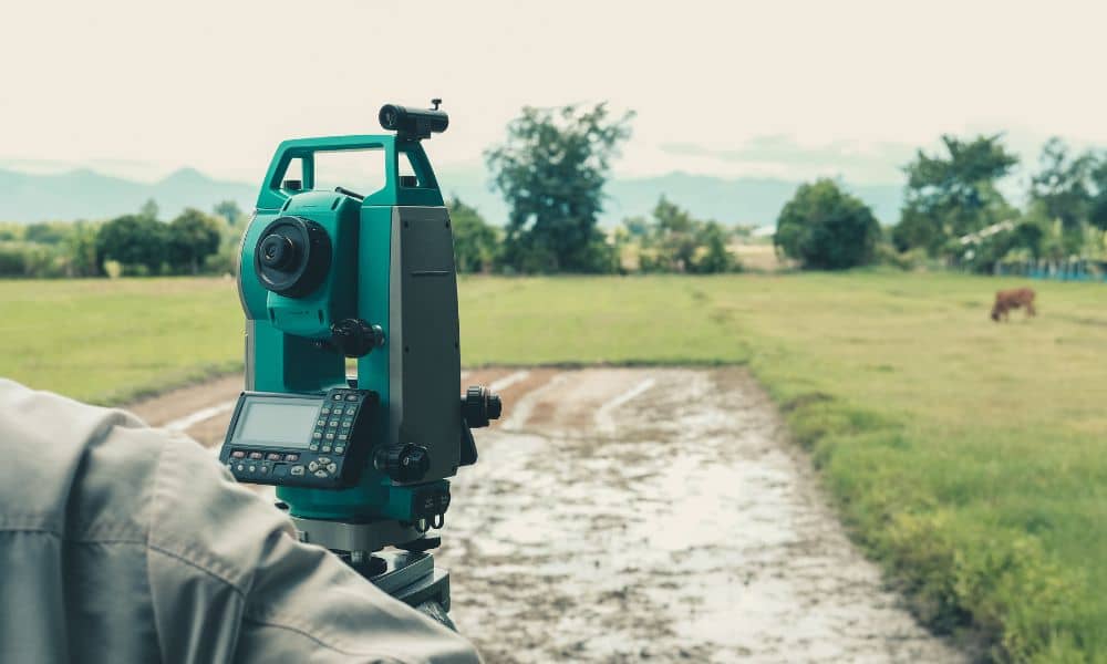 Surveyor using a total station during an ALTA survey on open land in Newnan