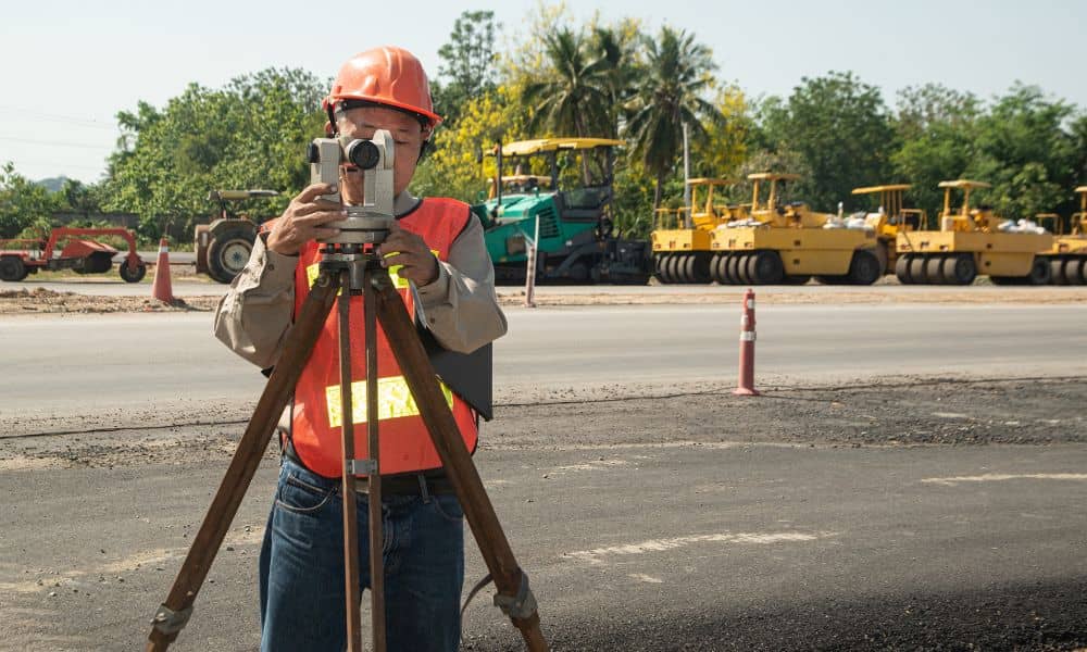 Land surveyor performing a boundary line survey on a roadway construction site to support new safety standards