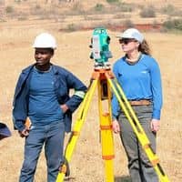 Licensed surveyors using field equipment to measure and mark property boundaries during a residential survey