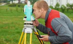 Licensed land surveyor measuring a home's height to prepare an elevation certificate for flood insurance review