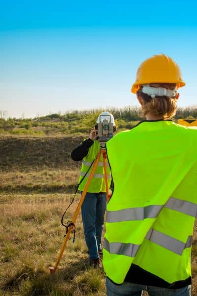Survey team using total station equipment in the field measuring land boundaries for cadastral survey work