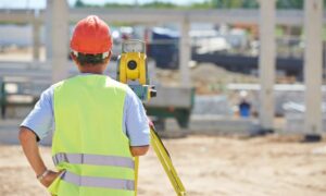 Surveyor using total station on construction site for elevation certificate and building approval process