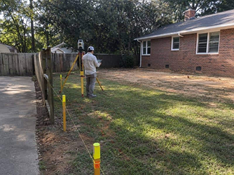 Property land survey stakes marking a Georgia home boundary before a rear renovation addition.